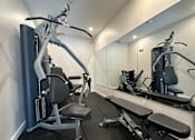 Thumbnail 13 of 16 - A gym with a mirror, a bench, and a leg press machine.