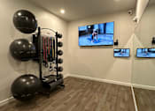 Thumbnail 12 of 16 - A home gym with a television screen showing a person exercising.