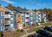 Thumbnail 1 of 30 - Apartment complex with cars parked in front.