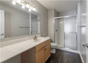 Thumbnail 19 of 19 - A bathroom with a sink, mirror, toilet, and shower.