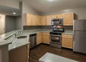 Thumbnail 14 of 19 - A kitchen with wooden cabinets and a granite countertop.