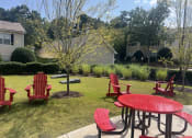 Thumbnail 38 of 40 - a patio with red chairs and a table in a yard at Addison on Cobblestone, Georgia