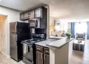 Thumbnail 4 of 40 - Kitchen with black appliances overlooking living room located at Addison on Cobblestone located in Fayetteville, GA 30215