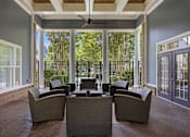 Thumbnail 30 of 42 - Covered patio with ceiling fan and wicker seating at Alden Place at South Square Apartments, Durham, NC 27707