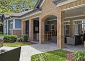 Thumbnail 31 of 42 - Covered outdoor patio with brick archway and seating at Alden Place at South Square Apartments, North Carolina