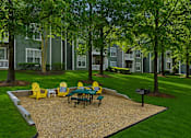 Thumbnail 28 of 42 - Outdoor picnic area with yellow adirondack chairs and gravel surface at Alden Place at South Square Apartments, North Carolina