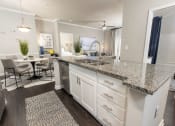 Thumbnail 4 of 40 - an open kitchen with granite counter tops and a dining room with a table at Ansley at Town Center in Evans GA