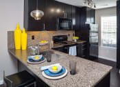 Thumbnail 21 of 40 - a kitchen with black cabinets and a granite counter top at Ansley at Town Center, Evans, GA, 30809