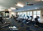 Thumbnail 4 of 30 - A gym with treadmills, elliptical machines, and other exercise equipment.