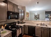 Thumbnail 13 of 30 - A modern kitchen with dark wood cabinets and black appliances.