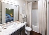 Thumbnail 28 of 30 - A bathroom with a white sink, toilet, and shower curtain.
