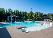 Thumbnail 17 of 30 - A pool with a gazebo and chairs in the foreground.