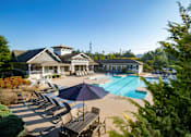 Thumbnail 18 of 30 - A large swimming pool with a blue umbrella and chairs around it.