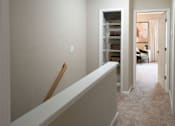 Thumbnail 13 of 26 - A hallway with a white wall and a white bench.