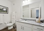 Thumbnail 7 of 18 - A white bathroom with a toilet, sink, and mirror at Arcadia Cartersville Apartments, Cartersville