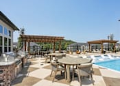 Thumbnail 11 of 18 - A poolside patio with a table and chairs at Arcadia Cartersville Apartments, Cartersville, 30121