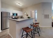 Thumbnail 2 of 36 - a kitchen with a breakfast bar and stools next to a washer and dryer at Autumn Park Apartments, Charlotte, 28262