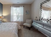 Thumbnail 7 of 36 - a bedroom with a large bed and a dresser with a mirror at Autumn Park Apartments, Charlotte, NC, 28262