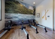 Thumbnail 20 of 36 - a row of exercise bikes in a room with a large painting on the wall at Autumn Park Apartments, Charlotte, NC