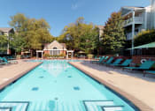 Thumbnail 12 of 36 - a swimming pool with blue chaise lounge chairs and a house in the background  at Autumn Park Apartments, Charlotte, North Carolina