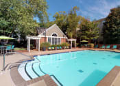 Thumbnail 14 of 36 - a swimming pool with lounge chairs and umbrellas in front of a building