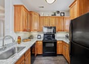 Thumbnail 2 of 19 - Gourmet Kitchens with Raised Panel Cabinetry, Granite Like Countertops, Black Appliance Packages and Lighting at Cambridge Square Apartments, Overland Park, KS 66211