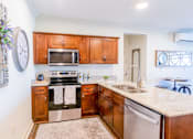 Thumbnail 2 of 25 - A kitchen with wooden cabinets and a stove top oven.at Carson Street Towers, Overland Park, 66223