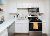 Thumbnail 2 of 12 - A modern kitchen with white cabinets and a black stove top. at Century Apartments, Memphis, 38117