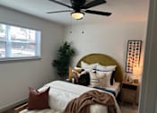 Thumbnail 3 of 9 - A bedroom with a bed, a ceiling fan, and a plant.at Century Apartments, Memphis Tennessee  