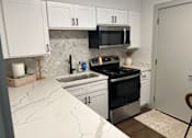 Thumbnail 4 of 9 - A kitchen with white cabinets and a black stove top oven.at Century Apartments, Memphis  