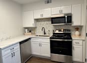 Thumbnail 7 of 9 - A kitchen with white cabinets and a black stove top oven.at Century Apartments, Memphis, TN 38117  
