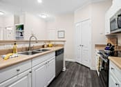 Thumbnail 11 of 42 - Galley kitchen with white cabinets and stainless steel appliances at Alden Place at South Square Apartments, North Carolina