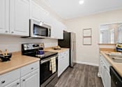 Thumbnail 2 of 42 - White kitchen with range microwave and refrigerator at Alden Place at South Square Apartments, Durham, NC 27707