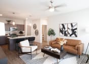 Thumbnail 3 of 17 - a living room with a ceiling fan and a kitchen in the background