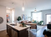 Thumbnail 1 of 17 - a kitchen with an island in front of a living room with a couch and chair