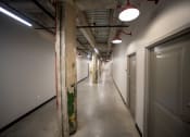 Thumbnail 7 of 23 - a view down a long corridor with white walls and grey doors at Conwood Flats, Memphis, TN, 38107