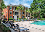 Thumbnail 17 of 29 - A pool surrounded by chairs and trees in front of a building.