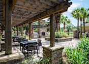 Thumbnail 20 of 29 - A patio with a table and chairs under a wooden roof.