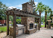 Thumbnail 21 of 29 - A brick oven is under a pergola in a backyard.