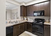 Thumbnail 1 of 29 - A kitchen with brown cabinets and black appliances.
