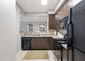 Thumbnail 2 of 29 - A kitchen with a black refrigerator and brown cabinets.
