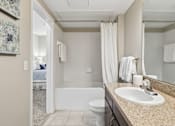 Thumbnail 9 of 29 - A bathroom with a white toilet, a sink, and a bathtub.