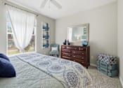 Thumbnail 8 of 29 - A bedroom with a bed, dresser, and mirror.