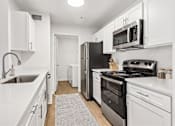 Thumbnail 8 of 33 - A kitchen with white cabinets and appliances.