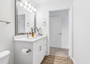 Thumbnail 16 of 33 - A white bathroom with a mirror, sink, and a white bathtub.