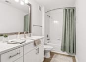 Thumbnail 15 of 33 - A white bathroom with a green shower curtain.