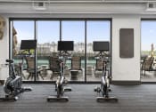 Thumbnail 20 of 41 - a gym with exercise machines and a view of a pool at Deca Apartments, South Carolina