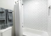Thumbnail 9 of 20 - A white tiled bathroom with a white tub at Dunwoody Glen, Atlanta Georgia