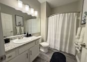 Thumbnail 8 of 22 - A bathroom with a white toilet, sink, and shower curtain at Enclave at Wolfchase Apartments, Tennessee 38016