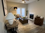 Thumbnail 5 of 22 - A living room with a fireplace, a chair, a table, and a lamp at Enclave at Wolfchase Apartments, Tennessee